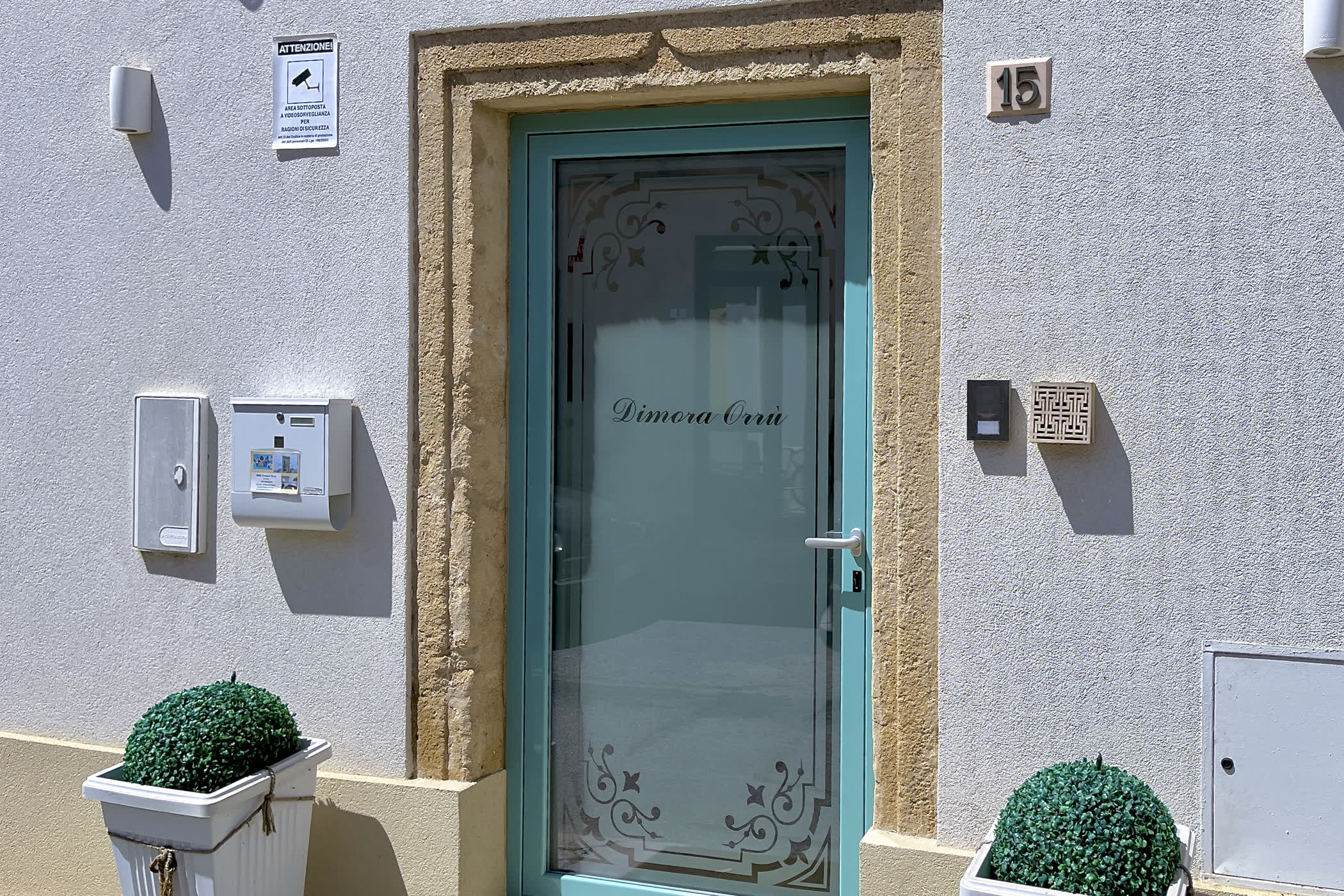 Ingresso di Dimora Orrù a Cabras, con porta turchese e cornice in pietra
